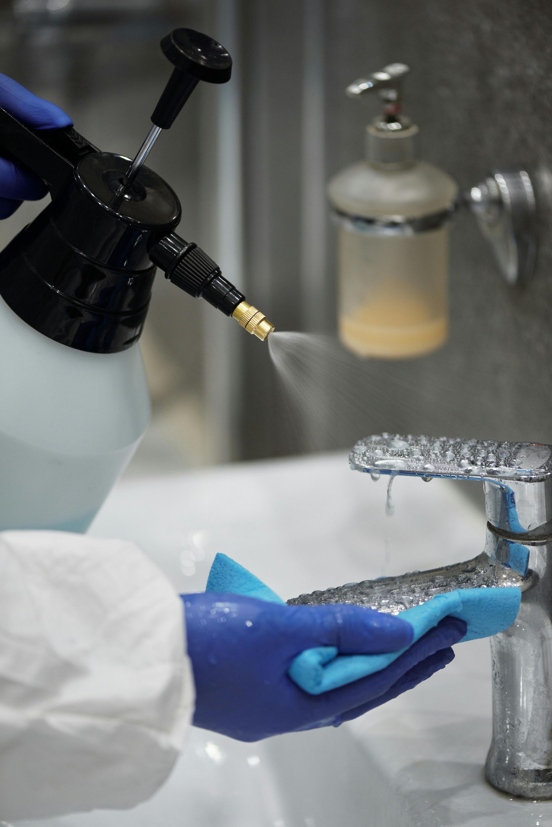 Una persona está limpiando un fregadero con una botella de spray y una esponja.