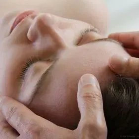 ProTherapie, Frau mit geschlossenem Augen wird von Händen an Stirn berührt