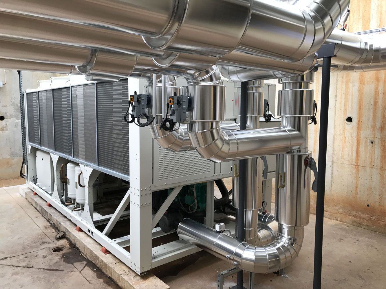 Grand refroidisseur industriel avec tuyaux argentés isolés dans une buanderie.