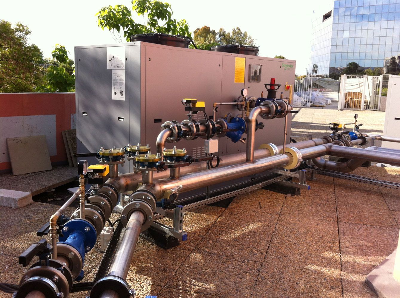 Système de refroidissement industriel avec tuyaux et vannes sur un toit.