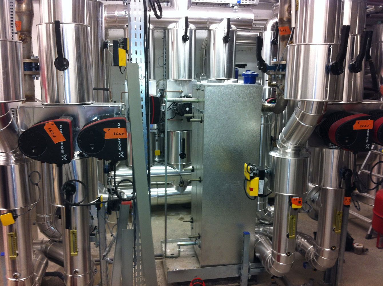 Machines industrielles en acier inoxydable avec tuyauterie et réservoirs cylindriques dans une installation.