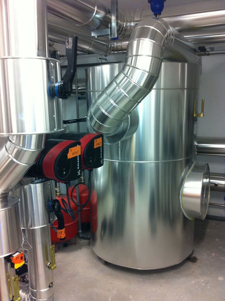 Équipements industriels, comprenant un réservoir cylindrique argenté et des pompes rouges, avec tuyauterie isolée.