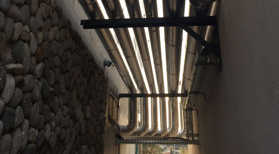 Un mur en pierre et un mur beige encadrent un auvent en métal et en plastique.