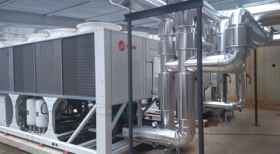 Unité de climatisation industrielle de grande taille, avec tuyaux argentés et châssis métallique.