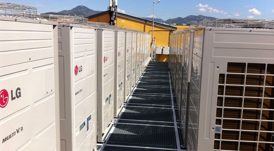 Des rangées d'unités de climatisation LG sur un toit, séparées par une passerelle.