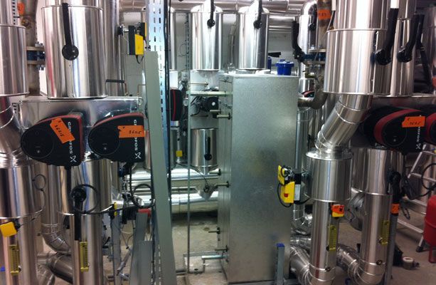 Tuyaux et réservoirs industriels dans une installation, avec un panneau de commande et divers manomètres.