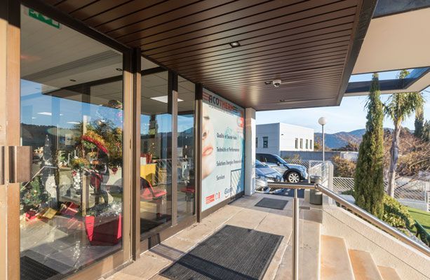 Vue extérieure d'un commerce avec des vitrines, des touches de brun et une rampe menant à l'entrée.