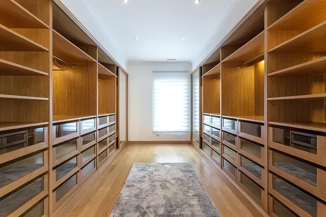 Cocina blanca con isla y taburetes, campana extractora de acero inoxidable, detalles en madera clara.