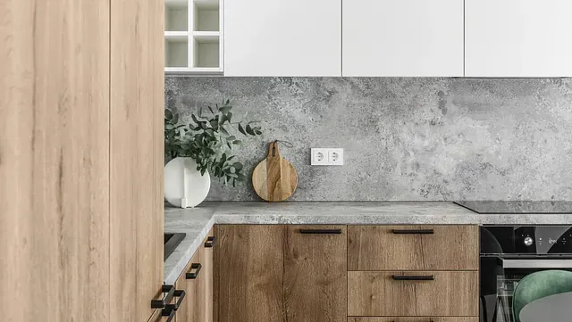 Cocina moderna con gabinetes de madera, salpicadero y encimeras de hormigón y grifo negro.