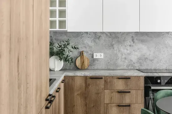 Cocina moderna con gabinetes de madera y blancos, protector contra salpicaduras gris y encimera con decoración.