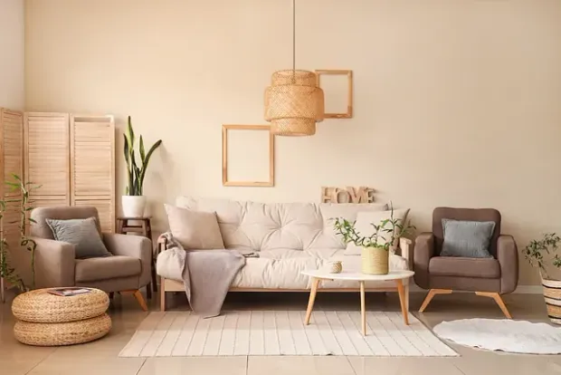 Acogedora sala de estar con paredes beige, sofá, sillones, plantas y detalles tejidos.