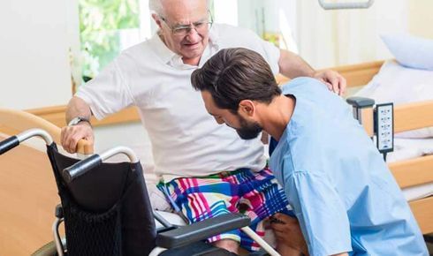 soignant aidant une personne âgée en fauteuil