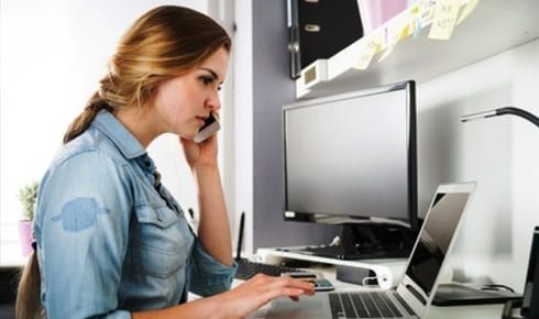 femme en chemise bleue travaillant sur un ordinateur