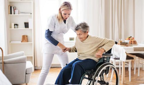 soignante aidant une personne en fauteuil à domicile