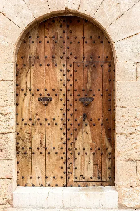 Una puerta de madera con un arco de piedra en el costado de un edificio.
