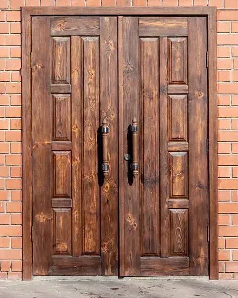 Un par de puertas de madera en una pared de ladrillos.