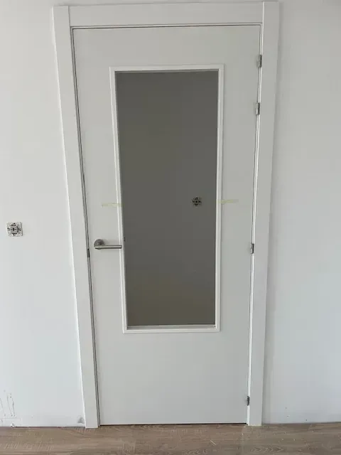 Una puerta blanca con una ventana de vidrio en una habitación.
