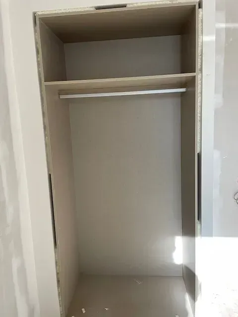 Un armario vacío con dos estantes y una percha.