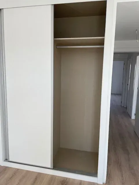 Un armario vacío con puertas correderas en un pasillo.