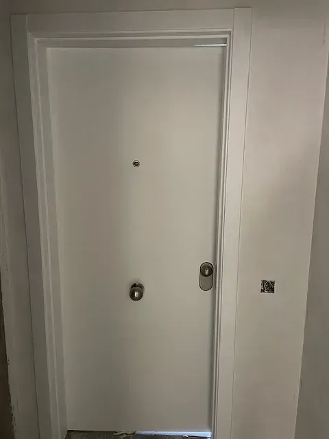 Una puerta blanca está en un pasillo al lado de una pared.