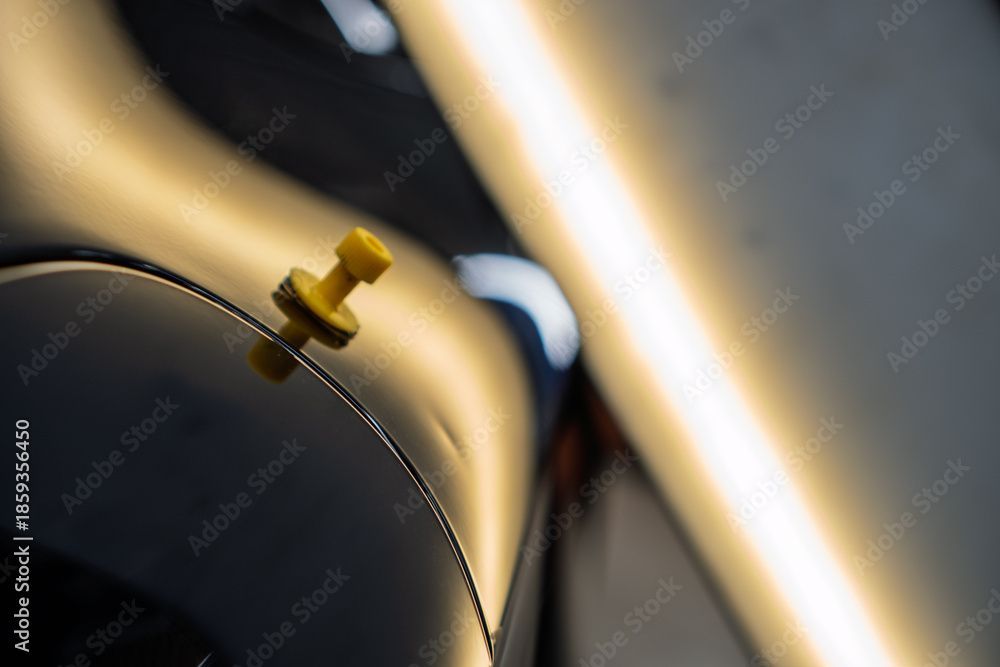 Nahaufnahme einer goldenen Uhr vor dunklem Hintergrund, mit sanften Spiegelungen und verschwommenen Lichtstreifen.