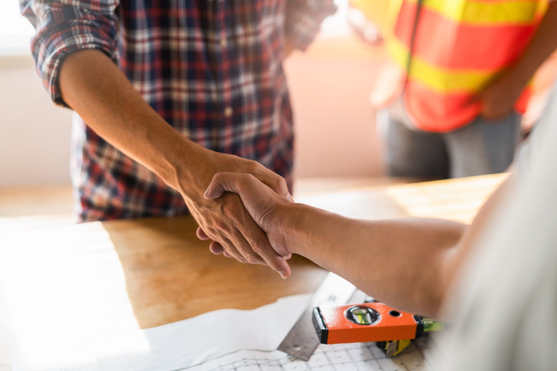 Una coppia di uomini si stringe la mano attorno a un tavolo.