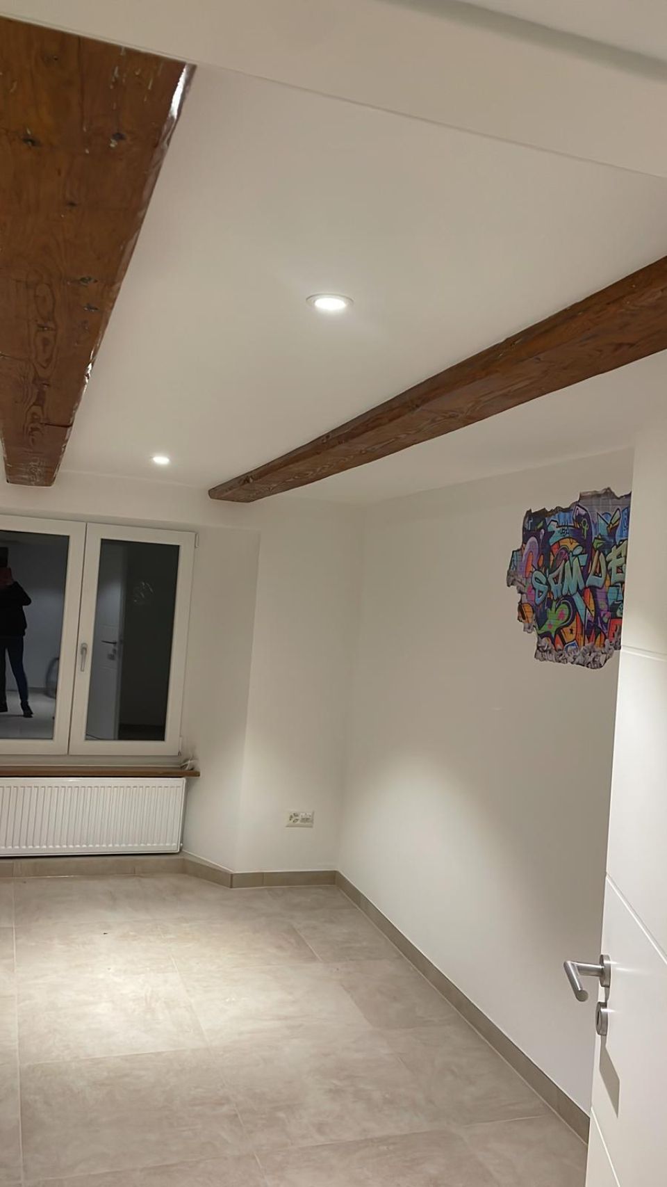 Una stanza vuota con un dipinto sul muro e una finestra.