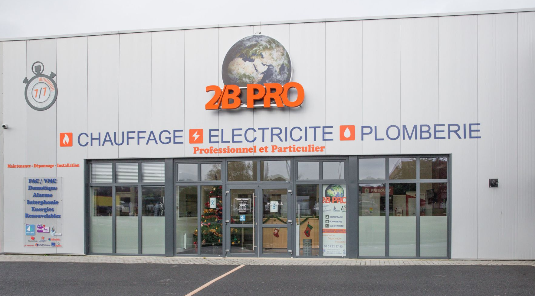 Façade de 2B Pro, un bâtiment gris avec des panneaux orange indiquant le chauffage, l'électricité et la plomberie.