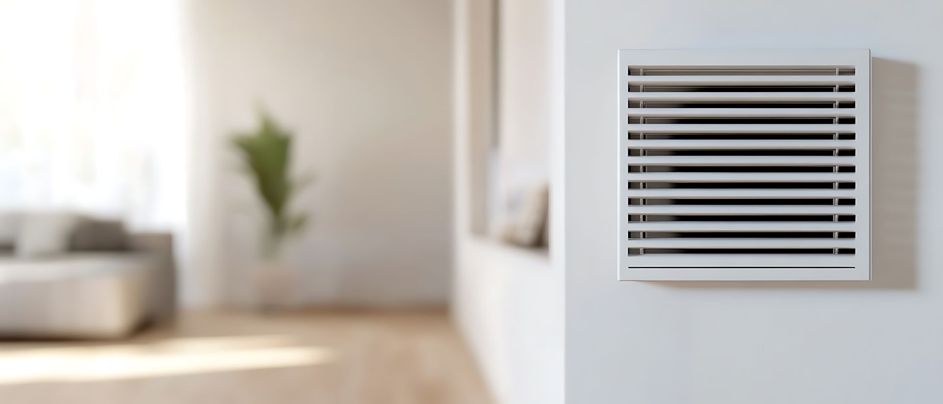 Grille d'aération blanche dans un salon lumineux et flou.