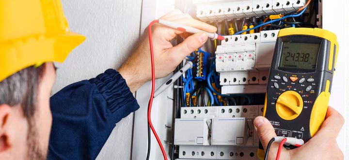 Un technicien teste un tableau électrique à l'aide d'un multimètre et de sondes.