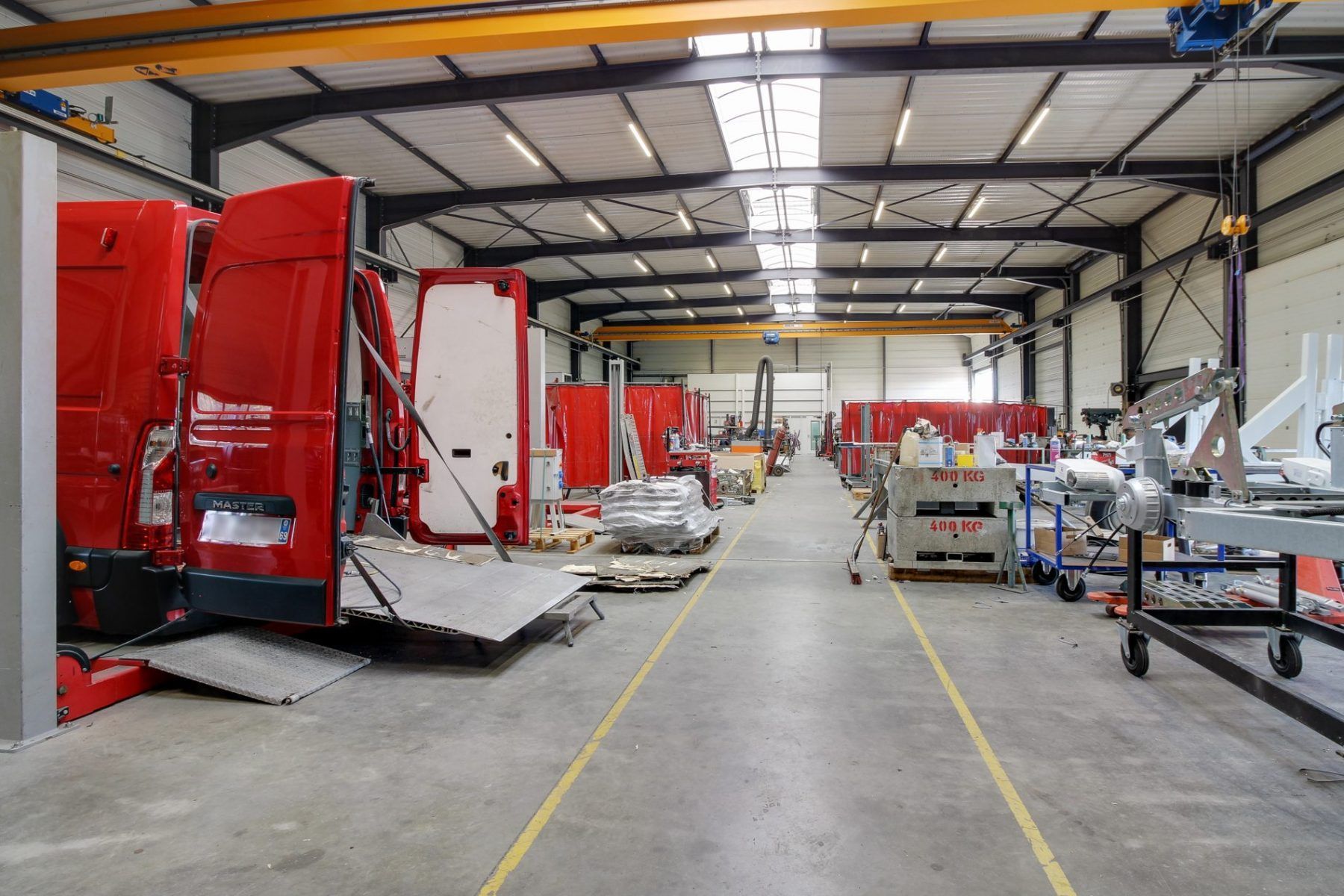Intérieur d'un grand atelier avec des pièces détachées de camions rouges, des outils et de l'équipement.