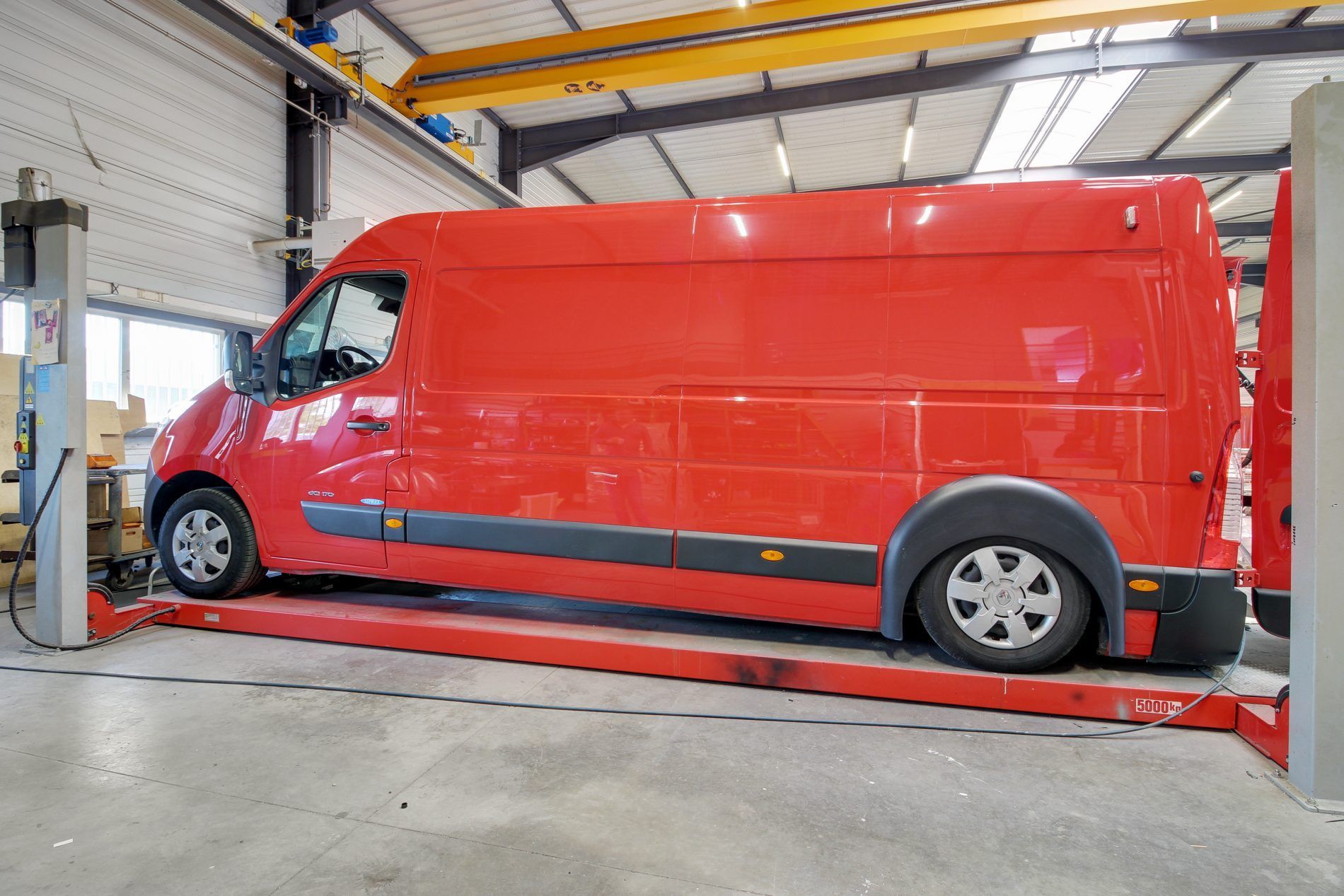 Une camionnette rouge sur un pont élévateur à l'intérieur d'un garage.