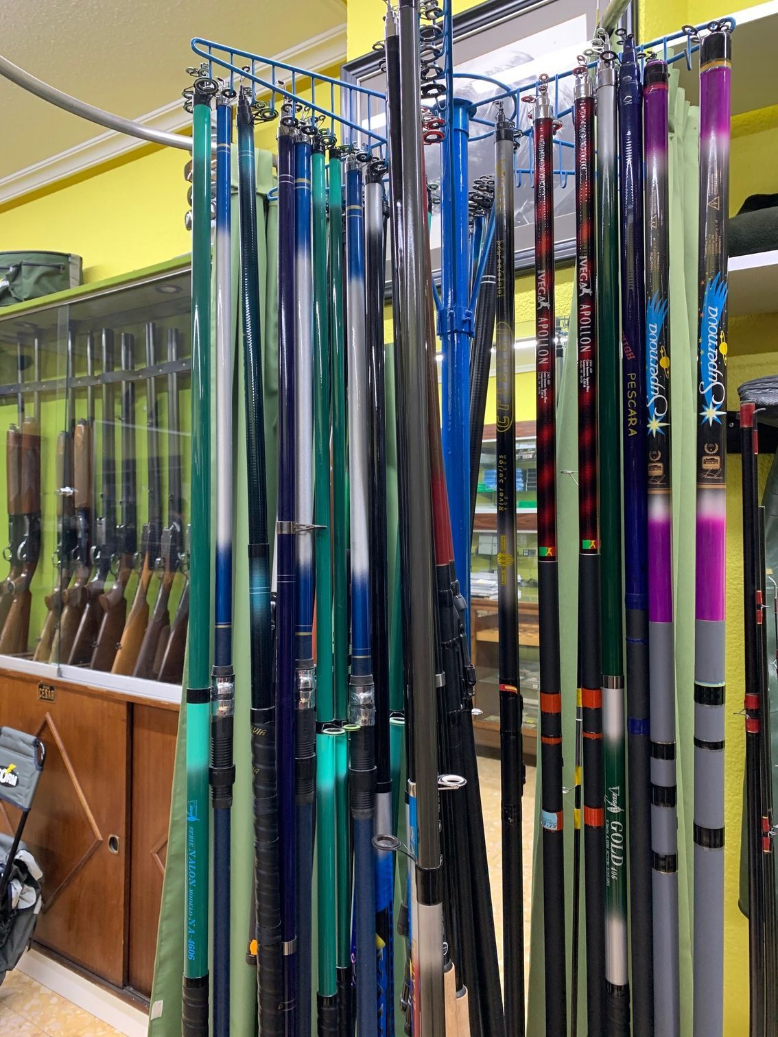 Un montón de cañas de pescar están colgadas en un estante en una tienda.