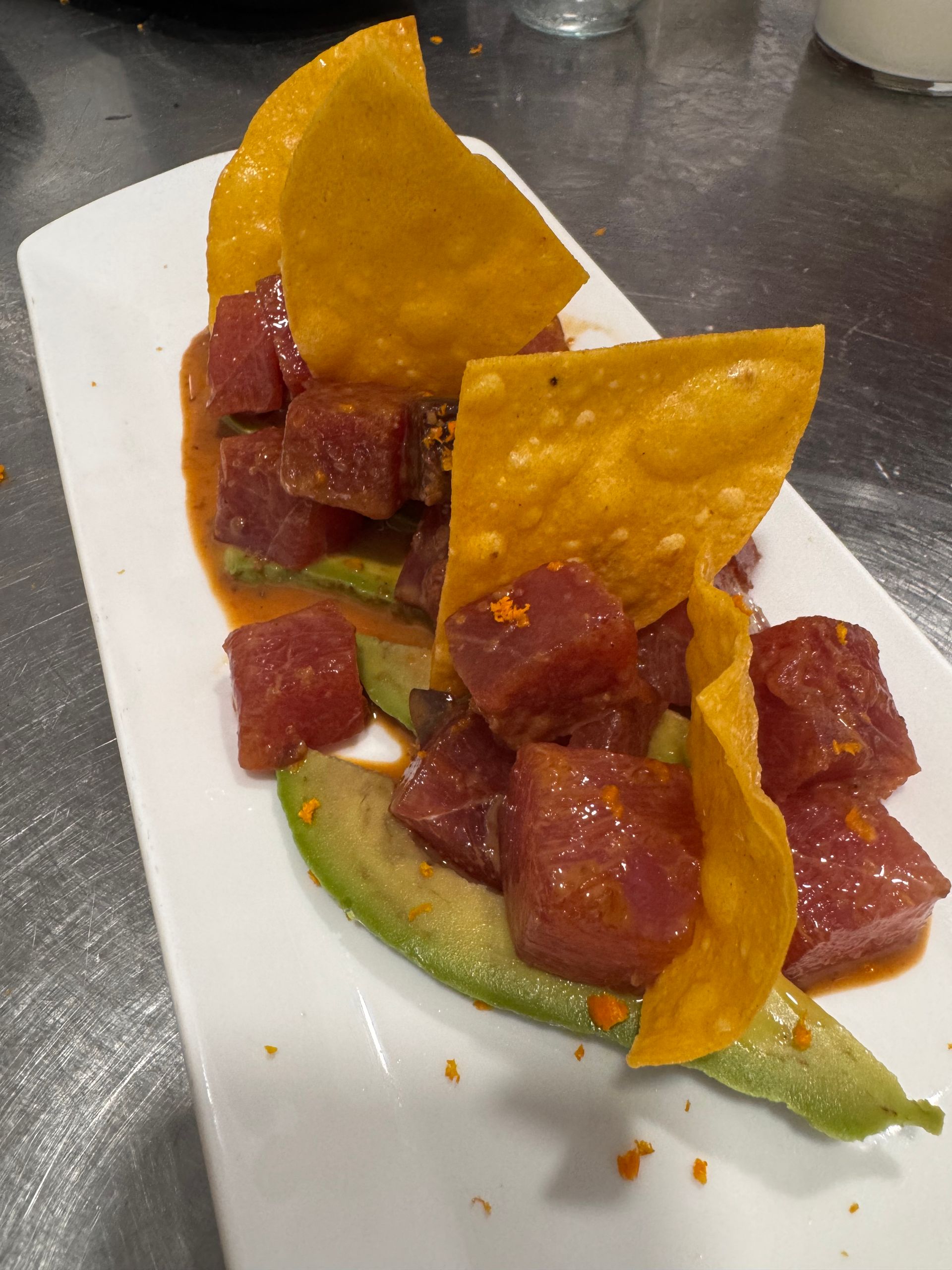 Plat de poke de tonyina amb alvocat i nachos en un plat rectangular blanc.