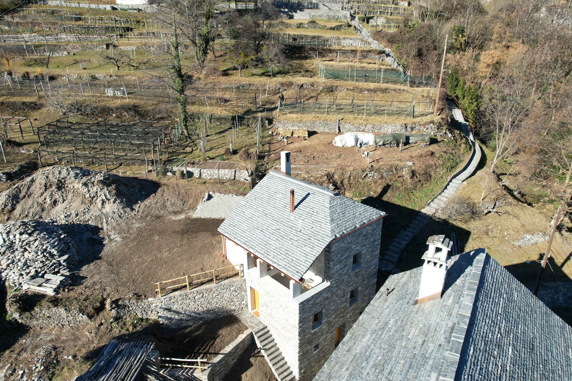 Tettisti al lavoro su un tetto complesso con struttura in legno, grondaie in rame e camini in mattoni.