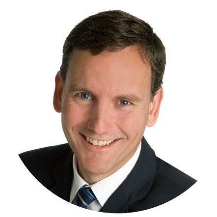 Mann mit Brille und hellblauem Hemd schaut in die Kamera.