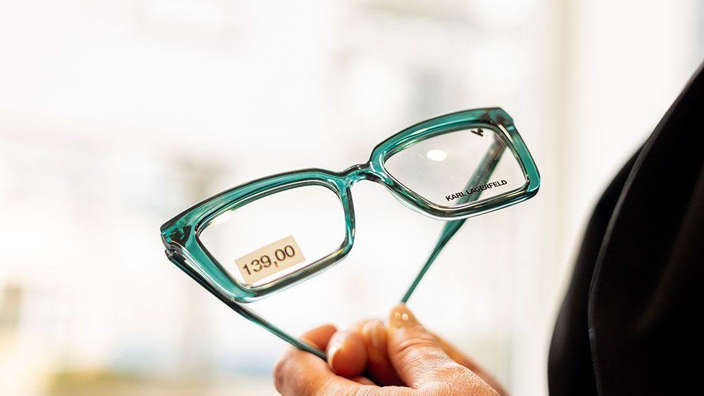 Eine Person hält eine Brille in der Hand.