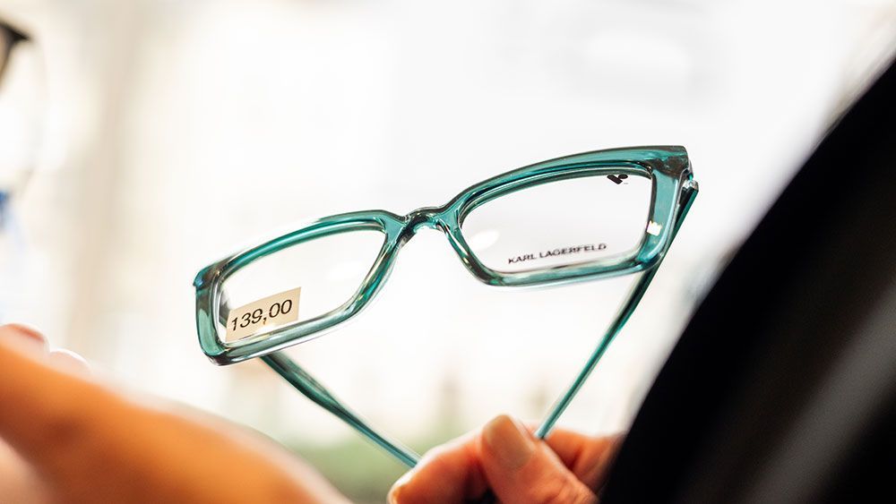 Eine Person hält eine Brille in der Hand.