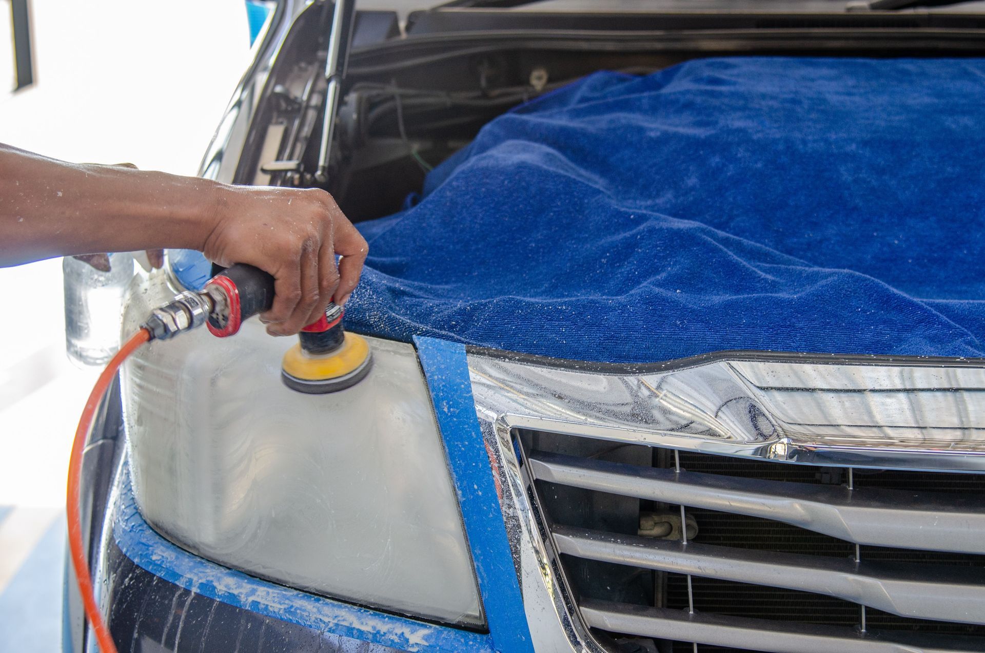 Un técnico limpiando el parabrisas de un coche en un taller mecánico