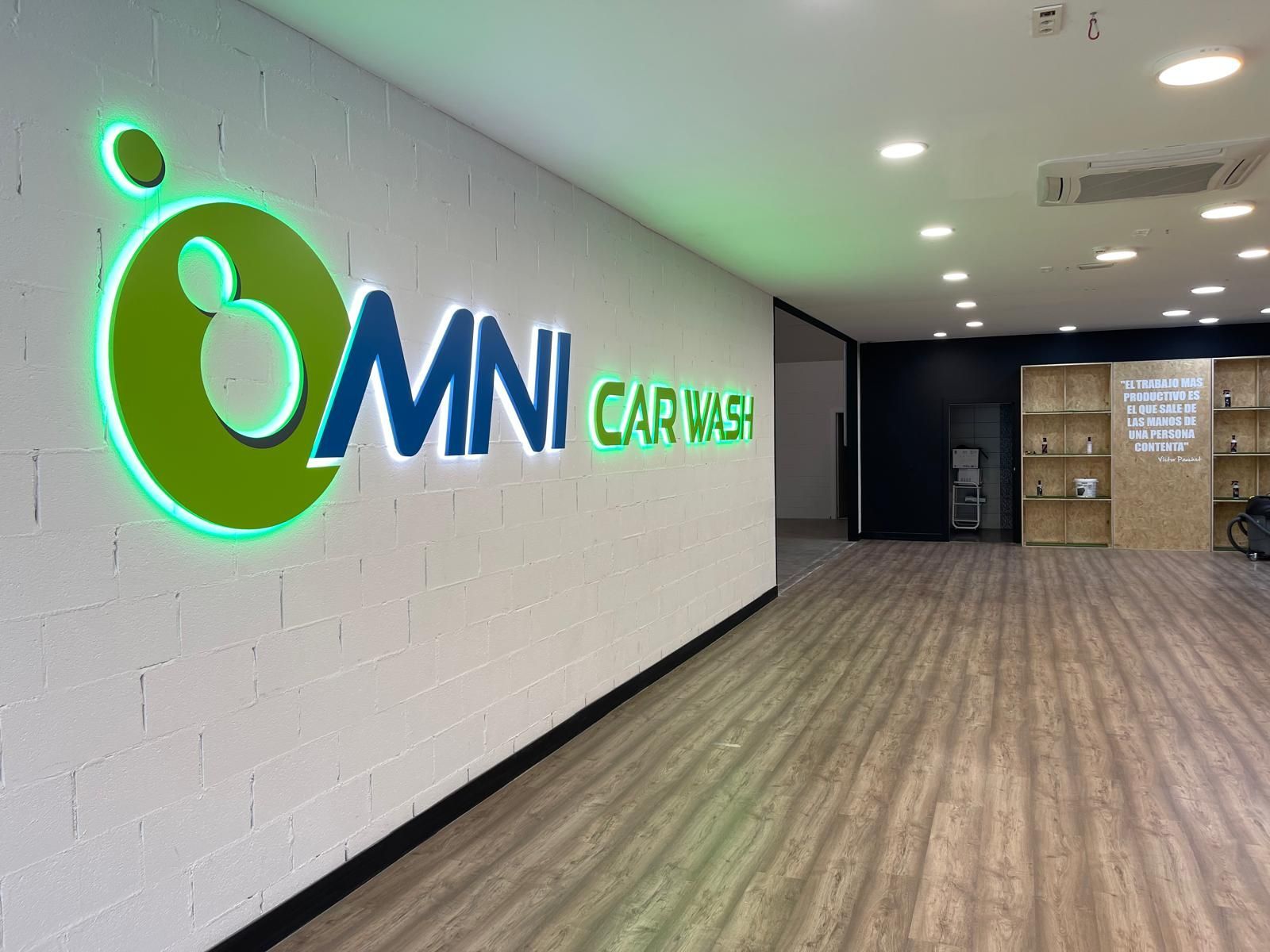 Dentro de OMNI Car Wash, un logotipo con detalles verdes y blancos está en una pared de ladrillos blancos.