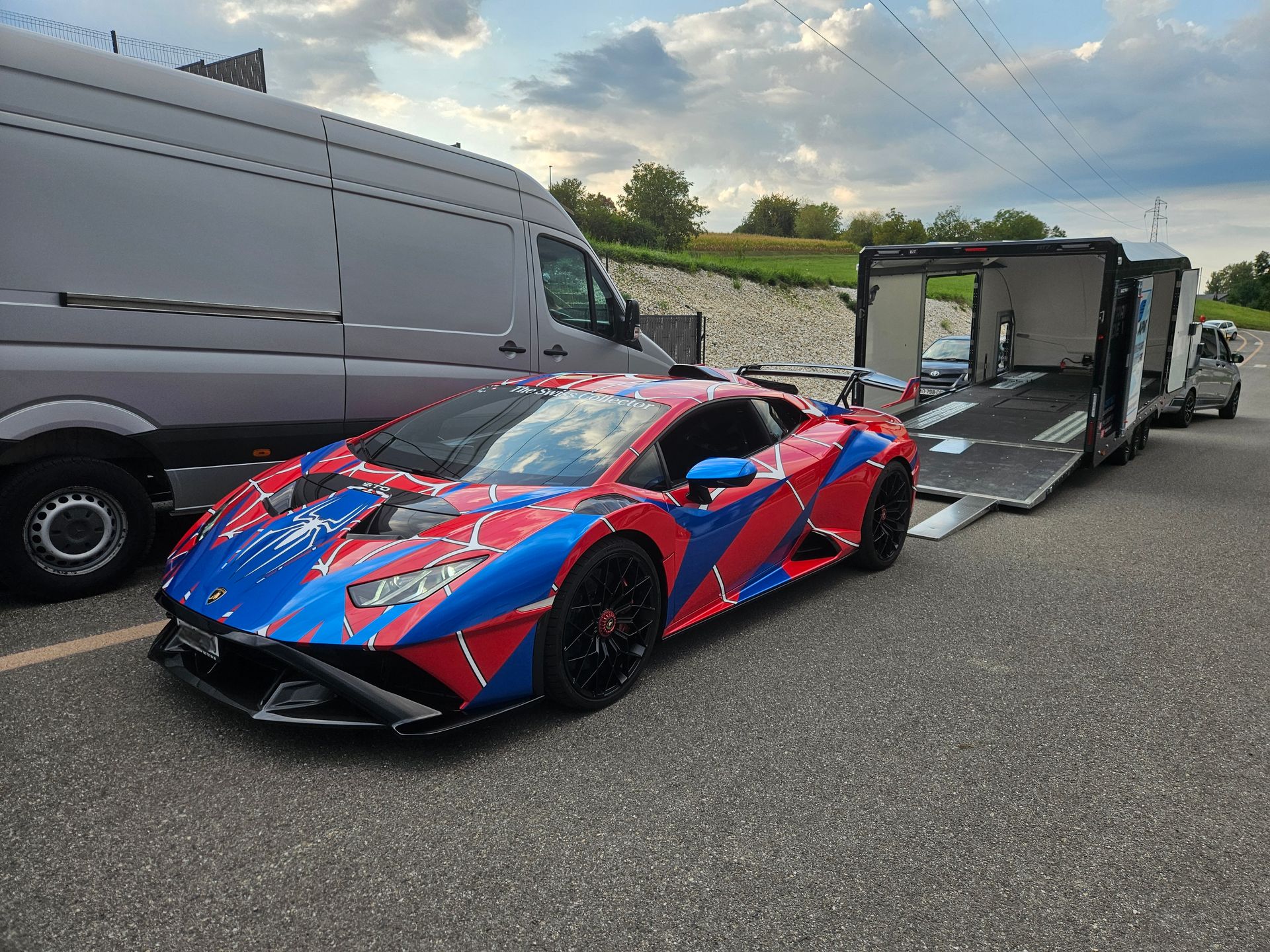 Un SUV Lamborghini Urus bleu foncé, arrimé par des sangles rouges à l'intérieur d'une remorque porte-voitures fermée.
