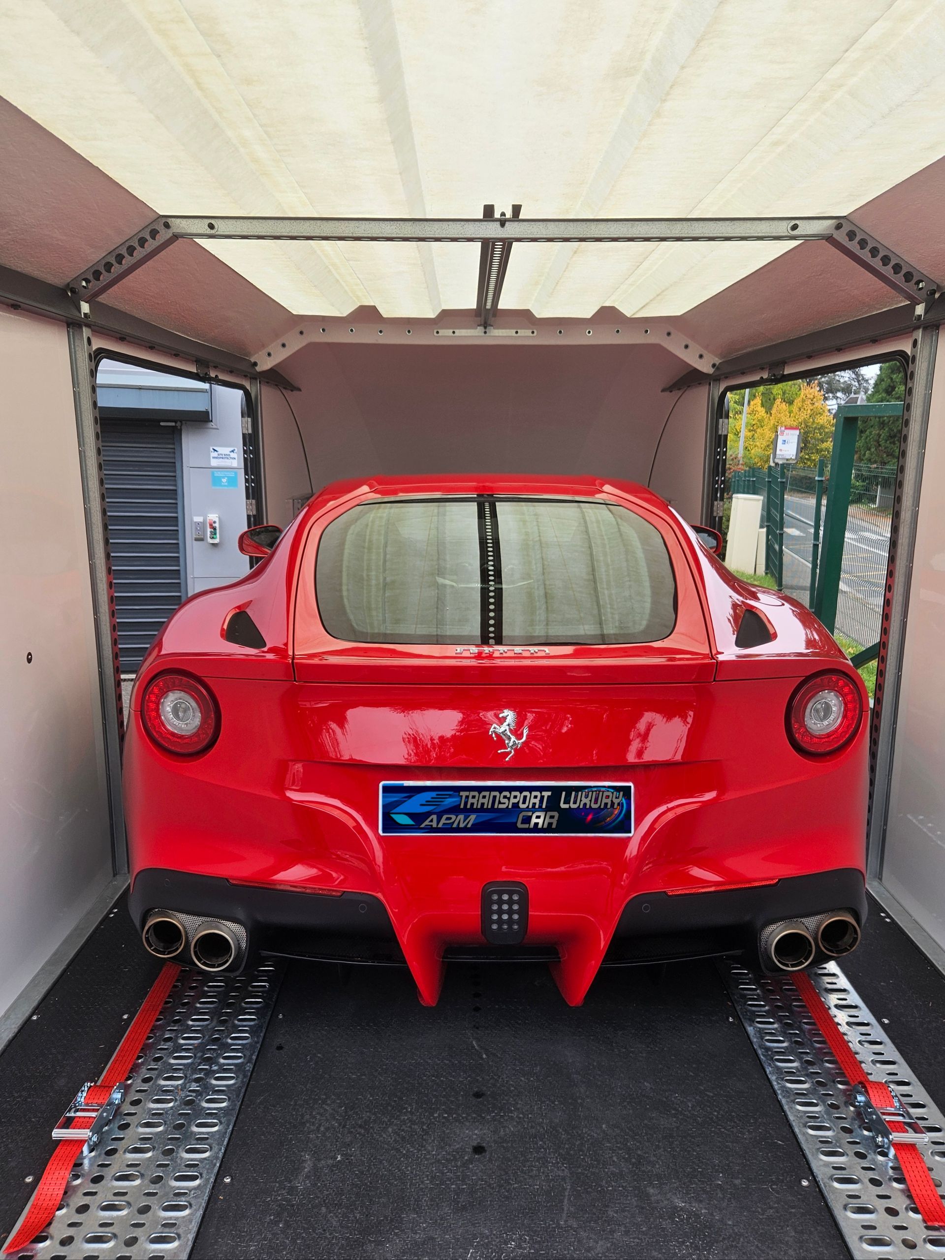 Une Ferrari rouge vif, voiture de sport, garée à l'intérieur d'une remorque porte-voitures couverte spéciale.