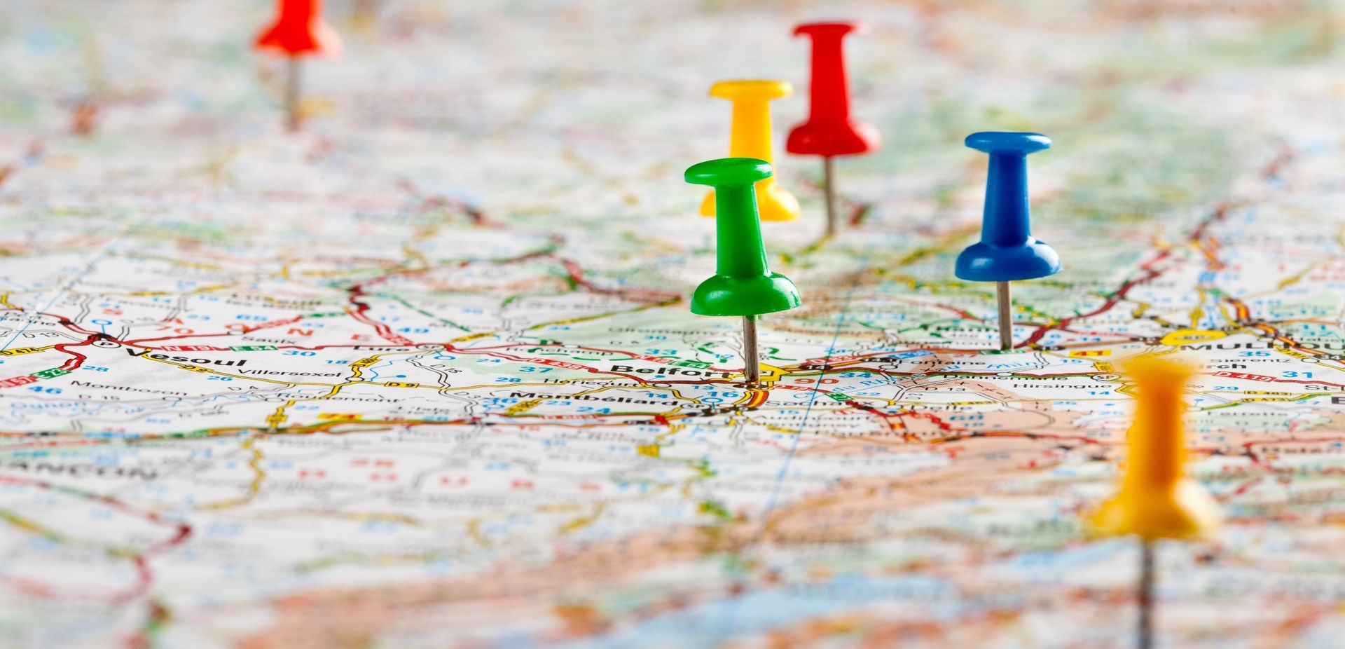 Gros plan d'une carte avec de nombreuses punaises colorées épinglées à différents endroits.