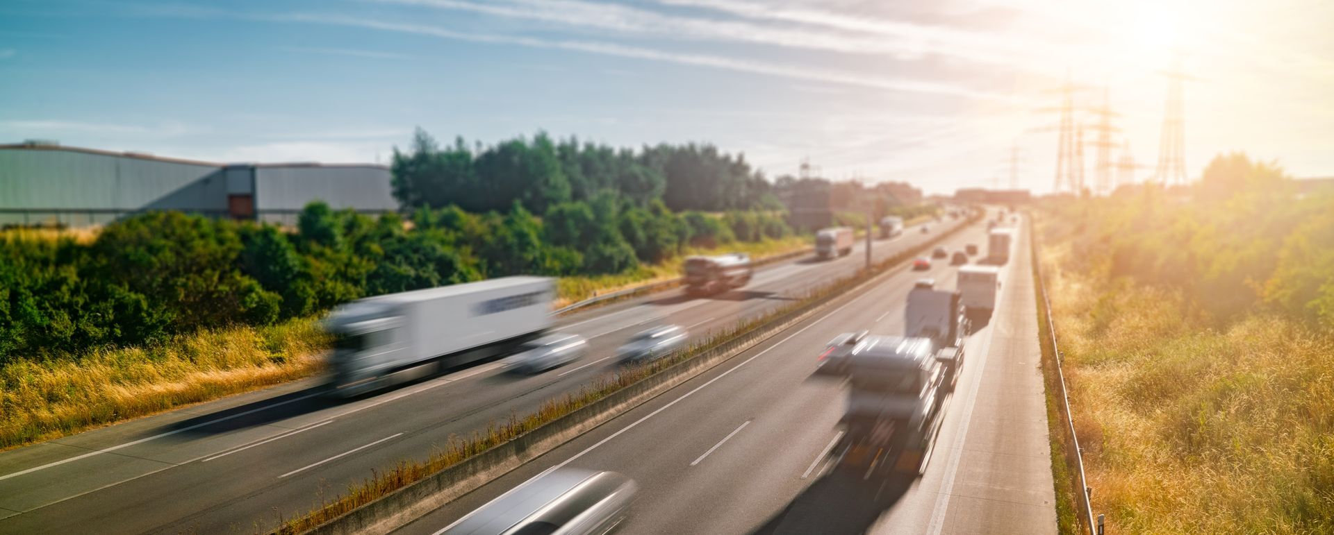 Des semi-remorques et des voitures circulent sur une autoroute par une belle journée ensoleillée.