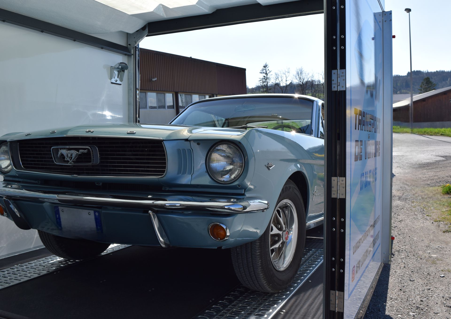 Une Ford Mustang bleue vintage garée dans une remorque par une journée ensoleillée.