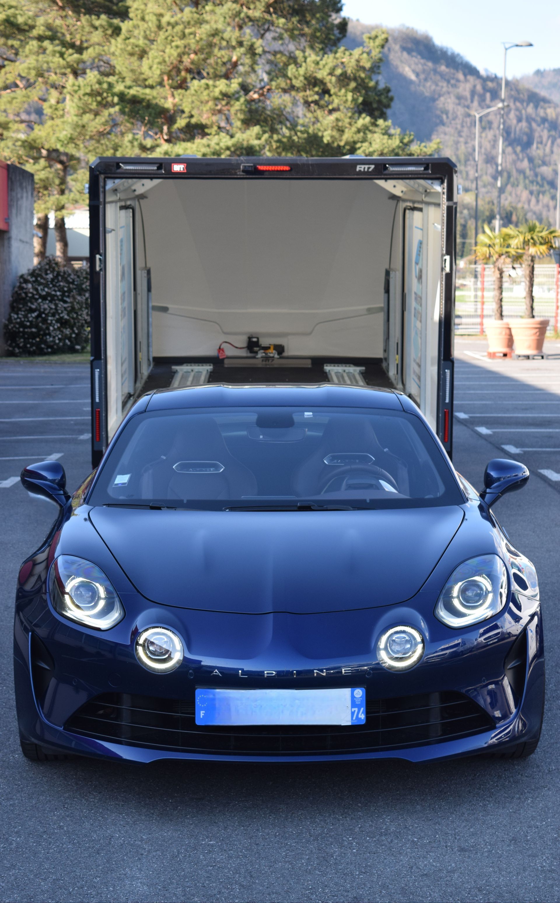 Une Lamborghini rouge et bleue aux couleurs de Spider-Man garée à côté d'une grande remorque et d'une camionnette.