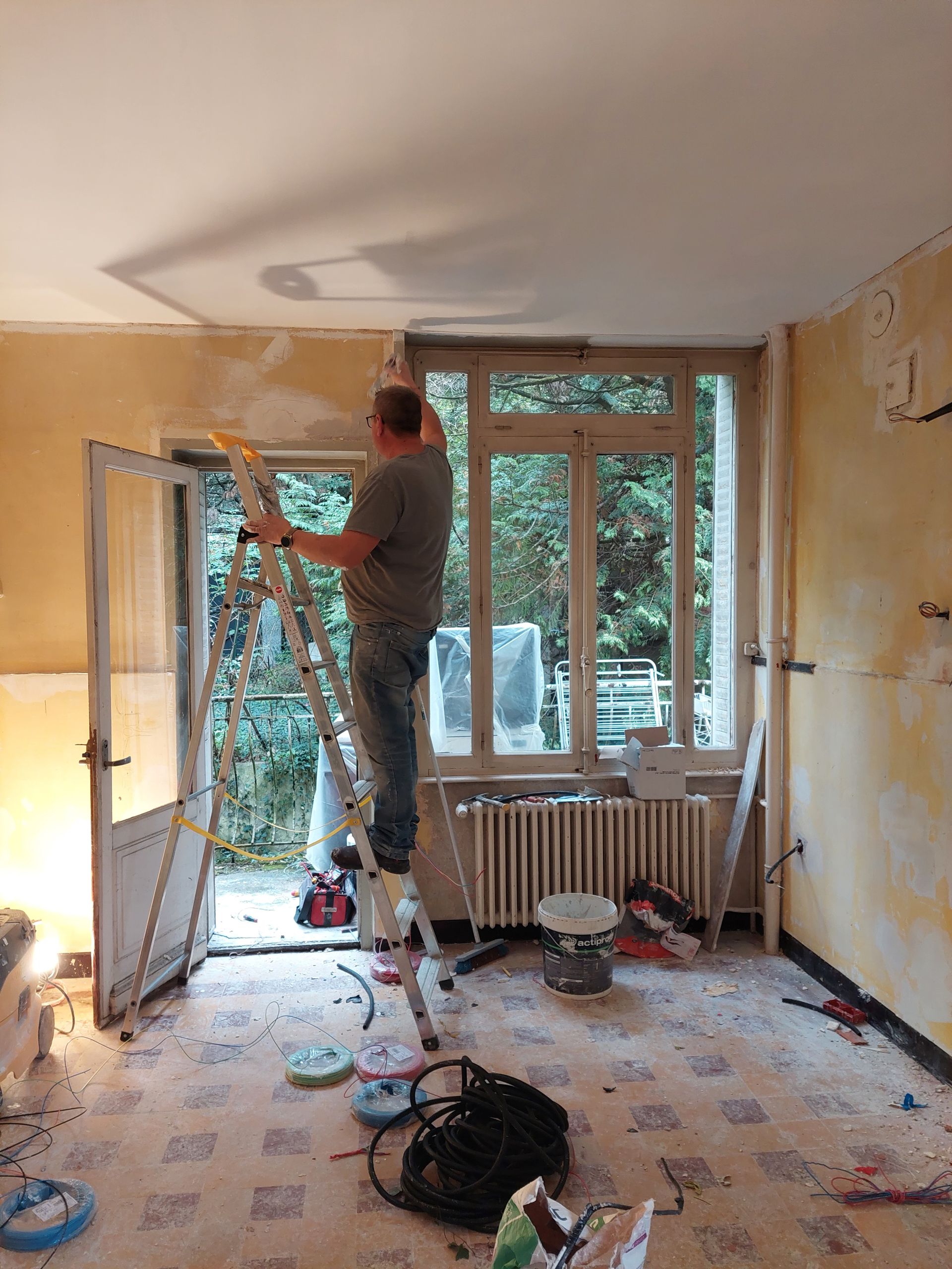 Homme sur un escabeau qui rénove une pièce