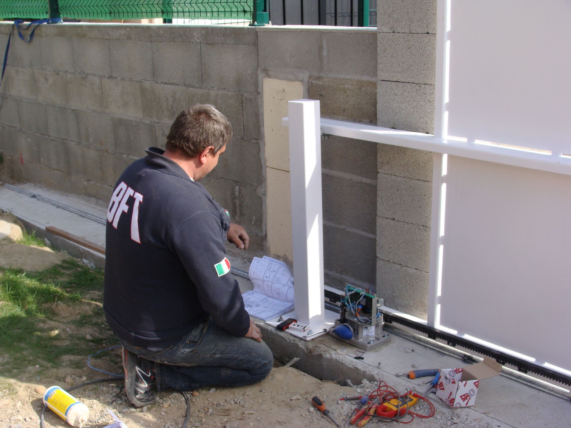 Homme qui installe un moteur à un portail blanc