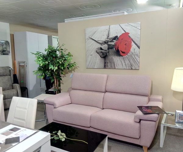 Una sala de estar con un sofá rosa y una imagen de una rosa roja en la pared.