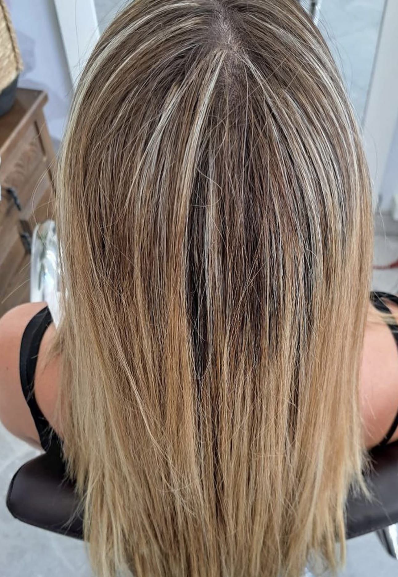 Una mujer con cabello largo y rubio está sentada en una silla.